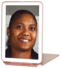Load image into Gallery viewer, Portable handheld Rose Gold travel mirror with brightness adjustable LED lighting and 3 color settings (cool white, warm white, and natural). A simple touch of the sensor creates the perfect light setting for your makeup routine! | Operating the LED lighting is simple — one tap of the sensor turns the light on and each additional tap cycles through the light colors. Press and hold the sensor to dim the brightness. | The lightweight and compact design makes this mirror your new travel buddy. Whet
